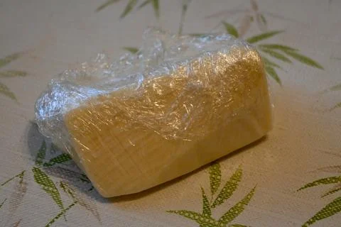 Trappista cheese wrapped in plastic on a table Stock Photos