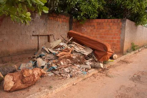 Trash and junk piled up on the side of the road near a house Fotos de archivo