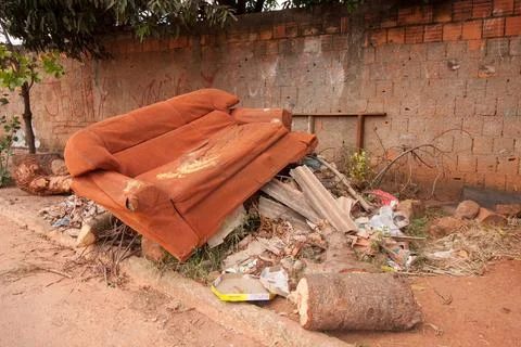 Trash and junk piled up on the side of the road near a house Stock Photos