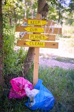 Trash bag next to sign to keep our planet clean.collecting garbage. Stock Photos
