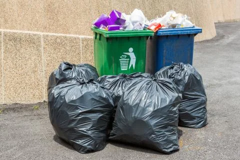 Trash bin and black garbage bag Stock Photos