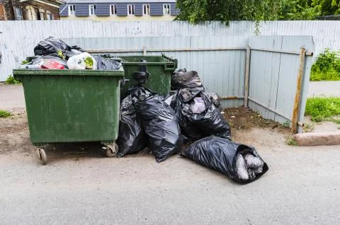 Trash bin and dumped garbage bags Stock Photos