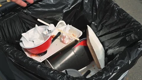 A trash bin contains food containers, plates, and utensils, showcasing waste Stock Footage 345886054