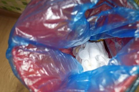 Trash bin filled with a blue garbage bag containing used diapers, symbolizing Stock Photos