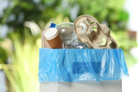 Trash bin with garbage on blurred background. Recycling problem Stock Photos