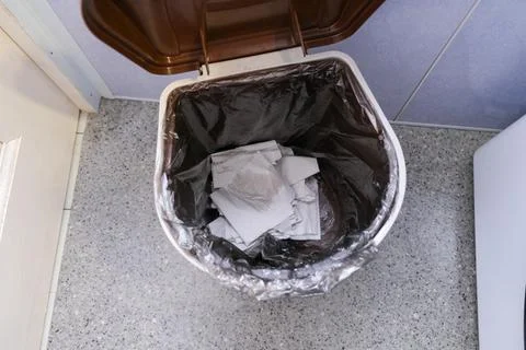 A trash bin with raised cap with used toilet paper, tissue in restroom Stock Photos