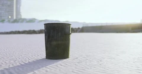 Trash bin stands alone on a clean sandy beach during sunset in a coastal city Ilustración de archivo