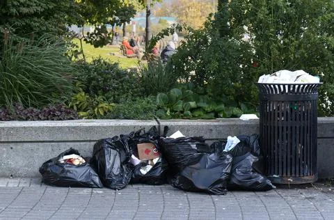 Trash can full of garbage in front of Stanley Park in Downtown Vancouver Stock Photos