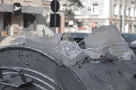 A trash can is full of garbage, including plastic bags. Stock Photos