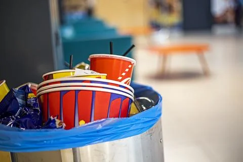 A trash can full of popcorn cups and drinks near the cinema exit after watc.. Stock Photos