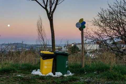 Trash cans lined up next to each other at sunset with the moon. Empremasa Stock Photos
