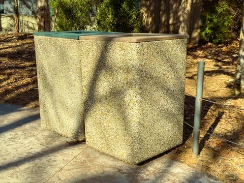 Trash cans sit side by side in an outdoor area surrounded by trees and brus.. Foto stock