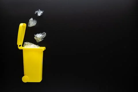 Trash plastic bin. Yellow dustbin for recycle plastic trash on black background Stock Photos