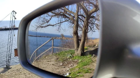 Trash on the road is reflected in the side mirror of the car. An electric motor  Stock Footage 126084057
