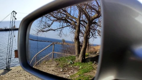 Trash on the road is reflected in the side mirror of the car. An electric motor  Stock Footage 126084064