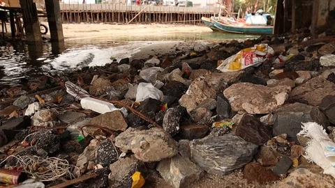 Trash in Rubble Under Bridge With Fishing Boats In Background Stock Footage