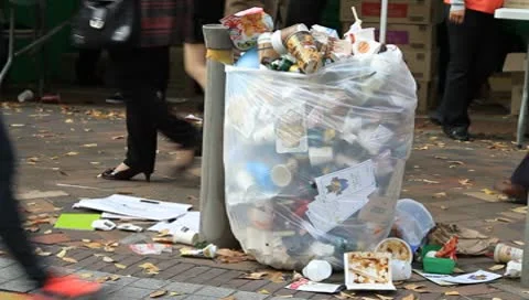 Trash spilling out of overfilled trash plastic bag on city street Stock Footage 8924796