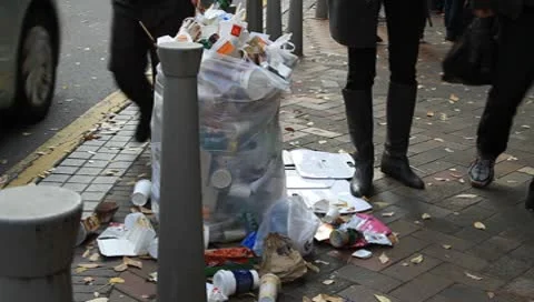 Trash spilling out of overfilled trash plastic bag on city street Video stock 8924801