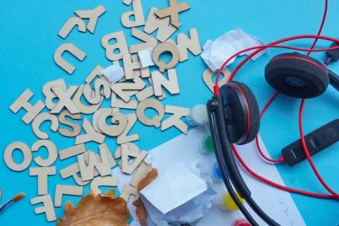 Trash on table or creative clutter, wooden letters, headphones, torn pieces o Stock Photos