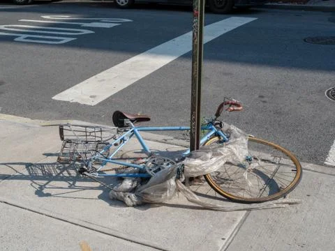Trashed bike wrapped in garbage broken on street corner Stock Photos