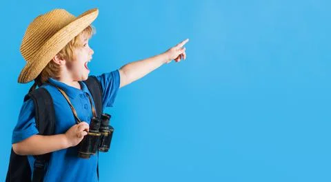 Travel and adventure. Happy kid boy with binoculars pointing finger at space  Stock Photos