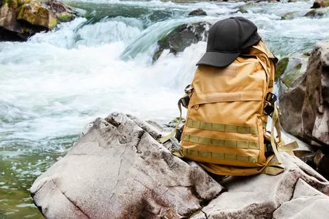 Travel backpack standing on forest river waterfall rock. 스톡 사진