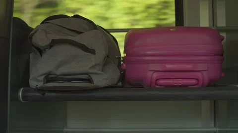 Travel bag and suitcase laying on a luggage rack of a train with moving scenery Stock Footage