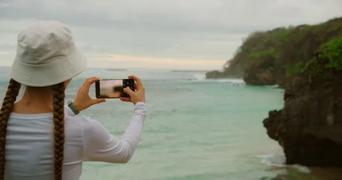 Travel content creation moment overlooking turquoise water and rocky shore Stock Footage 339276533