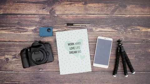Travel kit camera notebook tripod and phone on wooden background - Stop motion Stock-Footage 106363811