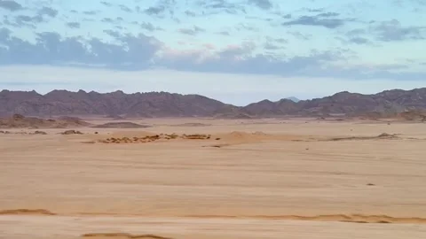 Travel scene featuring motion blurred vehicle view over vast rocky desert Stock Footage 326169921