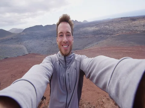 Travel tourist man taking selfie video hiking in volcano mountains of Lanzarote Stock Footage
