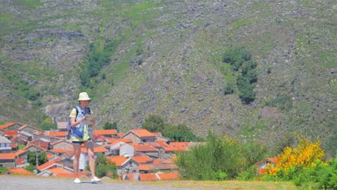 Traveler with backpack and map in hands on mountain landscape with village Stock Footage 92098341