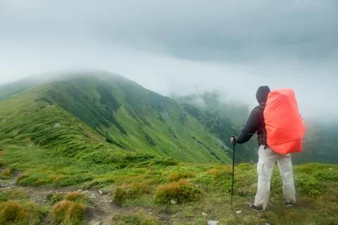 Traveler with backpack in the mountains in the clouds Stock Photos