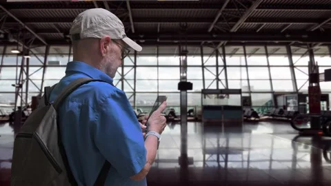 Traveler in Blue Shirt With Backpack Using Smartphone at Airport Terminal Stock Footage 329906220