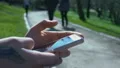 Traveler checking city maps in smartphone application, sitting in park, booking HD Footage