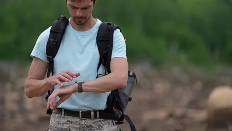 Traveler checking smartwatch during hike, carrying backpack Video stock 345886942