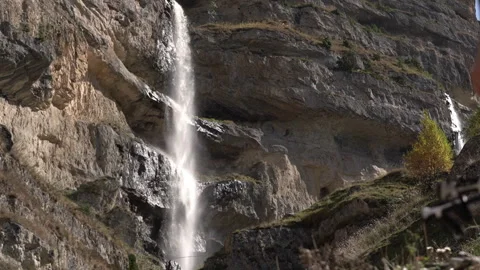 Traveler Passing in Front of Camera with Mountain Waterfalls Behind Stock Footage 327052393