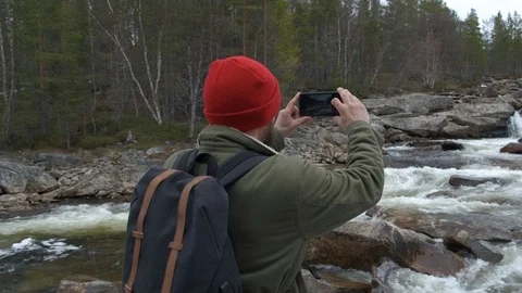 Traveler in a red hat with a backpack full back stopped to take a photo of a Stock Footage 109377672
