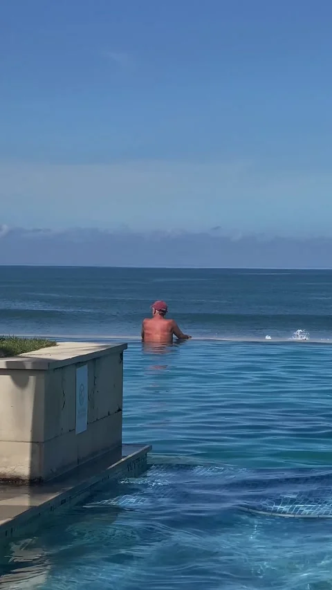 Traveler Rests By Bali Infinity Pool With Blue Waters Merging Into Ocean Horizon Vídeos de archivo 335591728