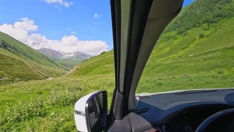 Traveler rests inside car, interior view across green highland terrain Stock Footage 343775181