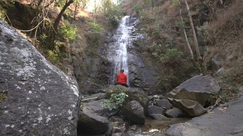 Traveler sit in front of waterfall in rainforest Stock Footage 87992140