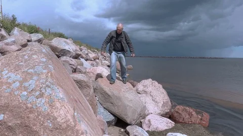 Traveler walking on rocky beach slope Stock Footage