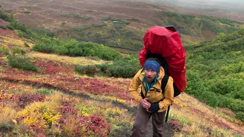 A traveler in a yellow jacket with a large backpack Stock-Footage 145184760