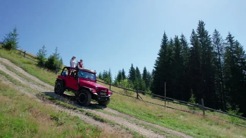 Travelers in open top SUV experience off road drive across mountain meadow road Stock Footage 346725549
