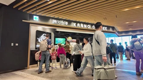 Travelers queue and walk past a Kanno Coffee shop. Video stock 346012822