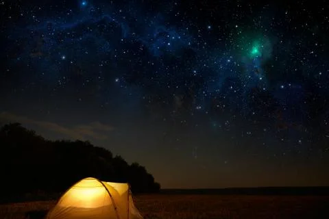 Traveling and camping concept - camp tent at night under a sky full of stars. Stock Photos