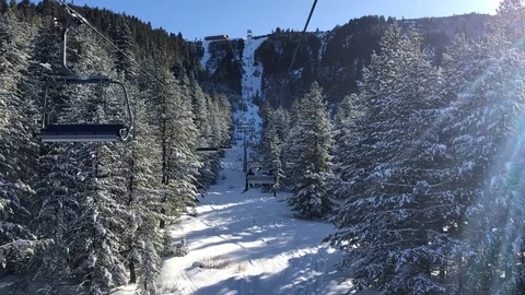 Traveling throw the snowy conifer forest on a chair lift . Backlit footage. Video stock 125958366