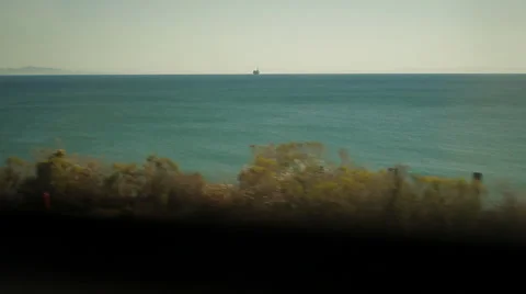 Traveling on train, looking out window viewing ocean &amp; oil rig-02 Stock Footage 43736874