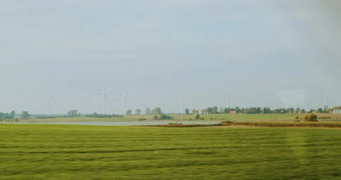 Traveling by train view from the side window to the fields with windmills Stock Footage 230681541