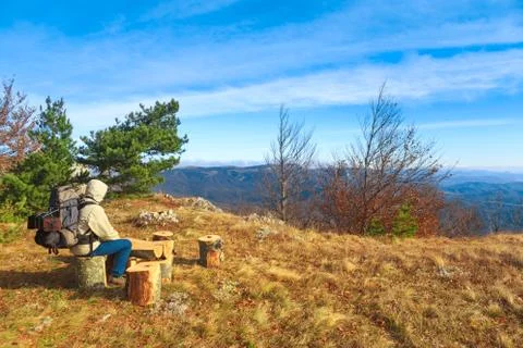 Traveller with a backpack sits on a tree stump and admires autumnal landsca.. Stock Photos